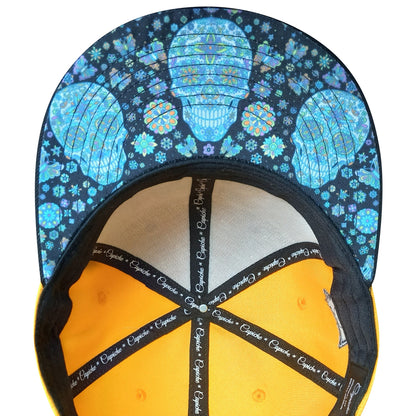 Cap with blue skull and flower pattern on top and yellow interior on a white background