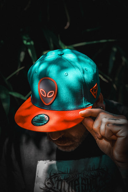 Tattoo Model Wearing Blue and Red Snapback Hat with Alien Front Logo From Capiche