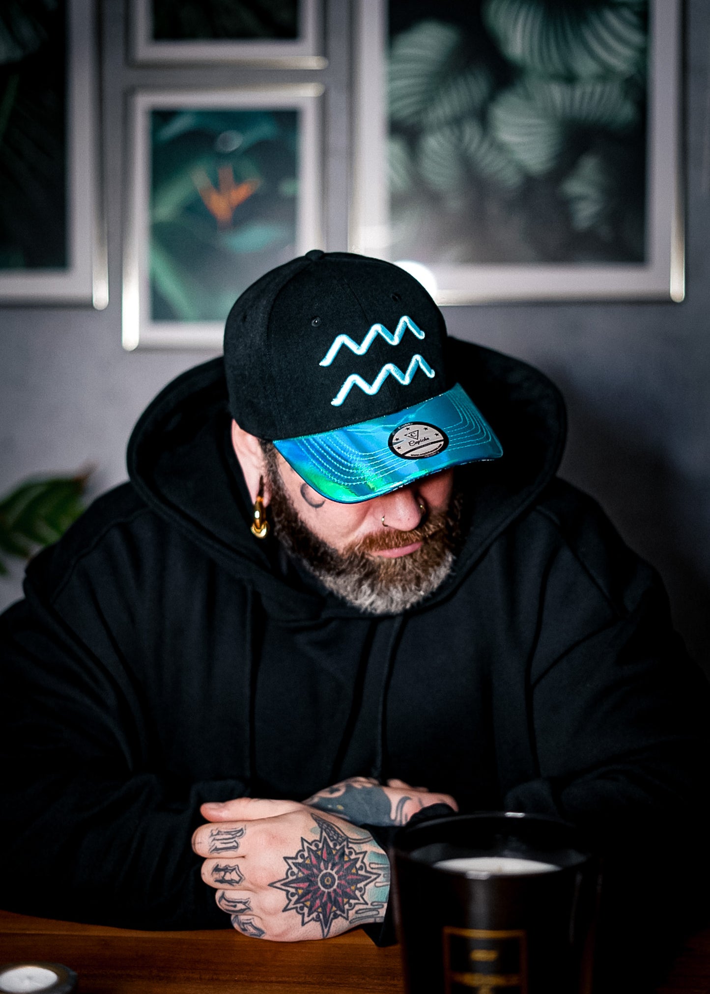 Tattooed man wearing a curved cap from Capiche with a special metallic visor in the color blue