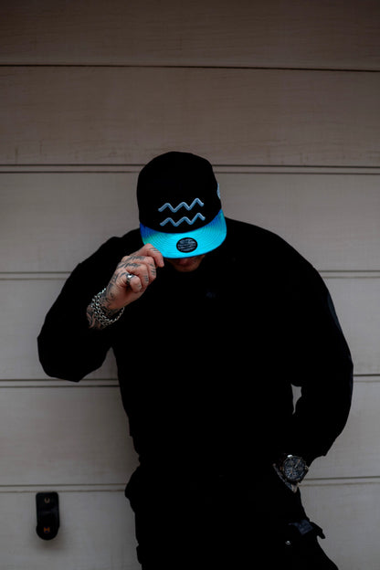 Tattoo Model with Aquarius Black Snapback On His Head with Blue Metallic Brim