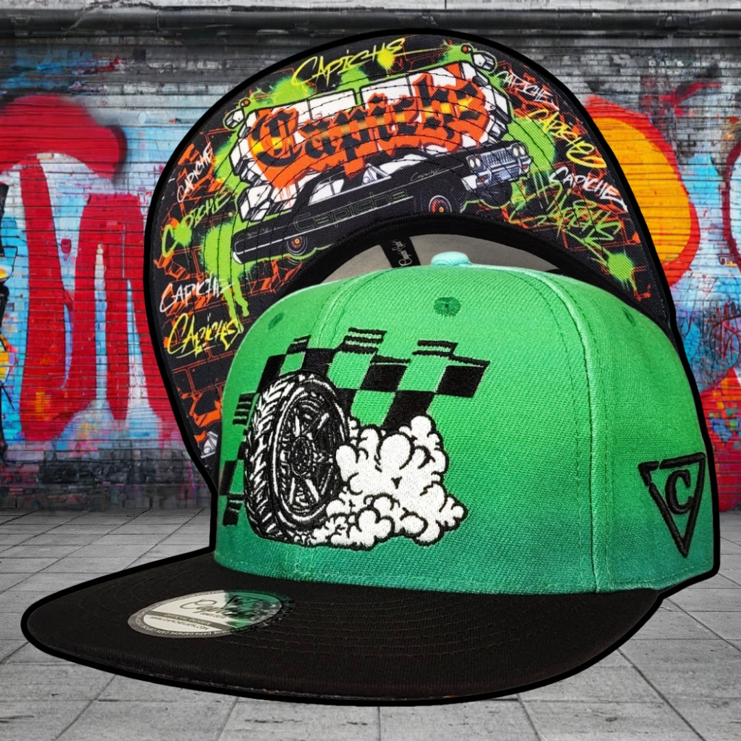 Two colorful caps with graphic designs against a graffiti-covered wall.