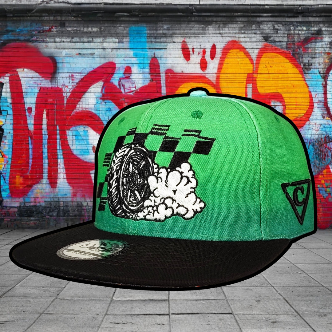 Green and black cap with graphic design on a graffiti-covered wall background