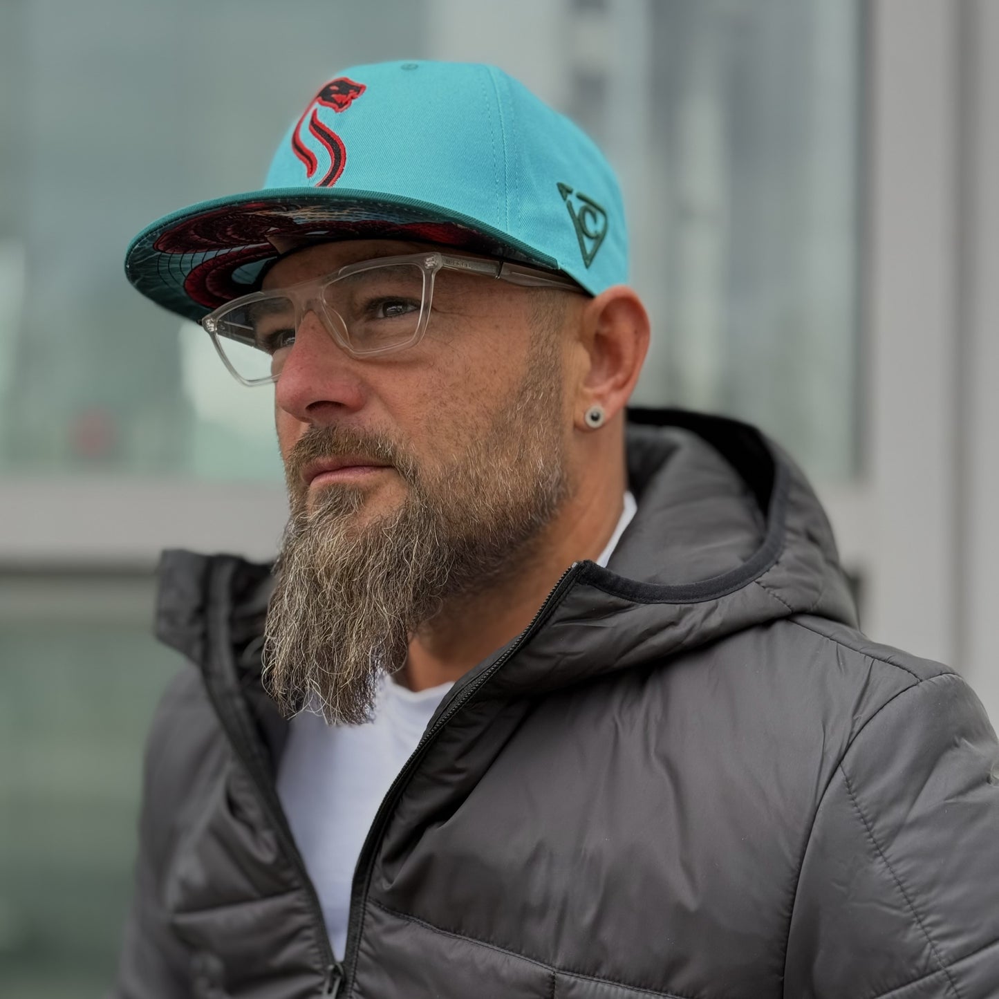 Man with beard standing outside with a blue snapback hat from headwear brand Capiche