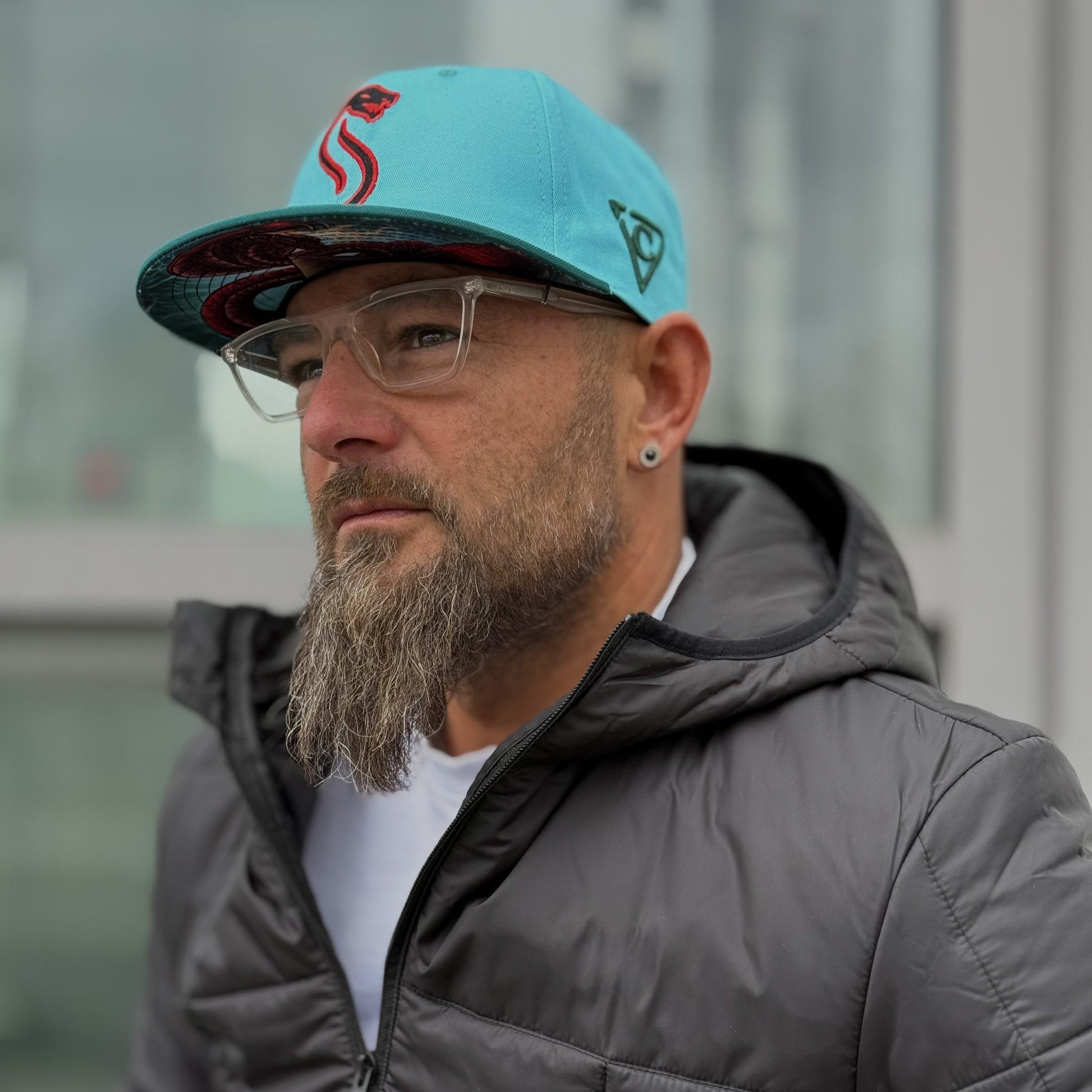 Man with beard standing outside with a blue snapback hat from headwear brand Capiche