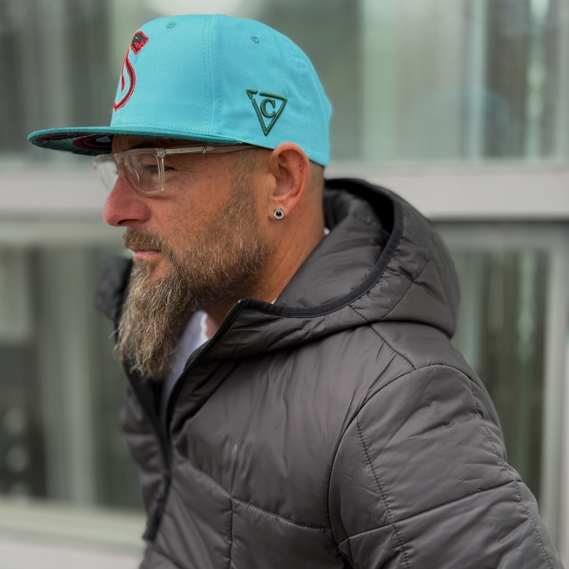 Side view of a man with a beard being photographed with the Fire Snake hat on his head