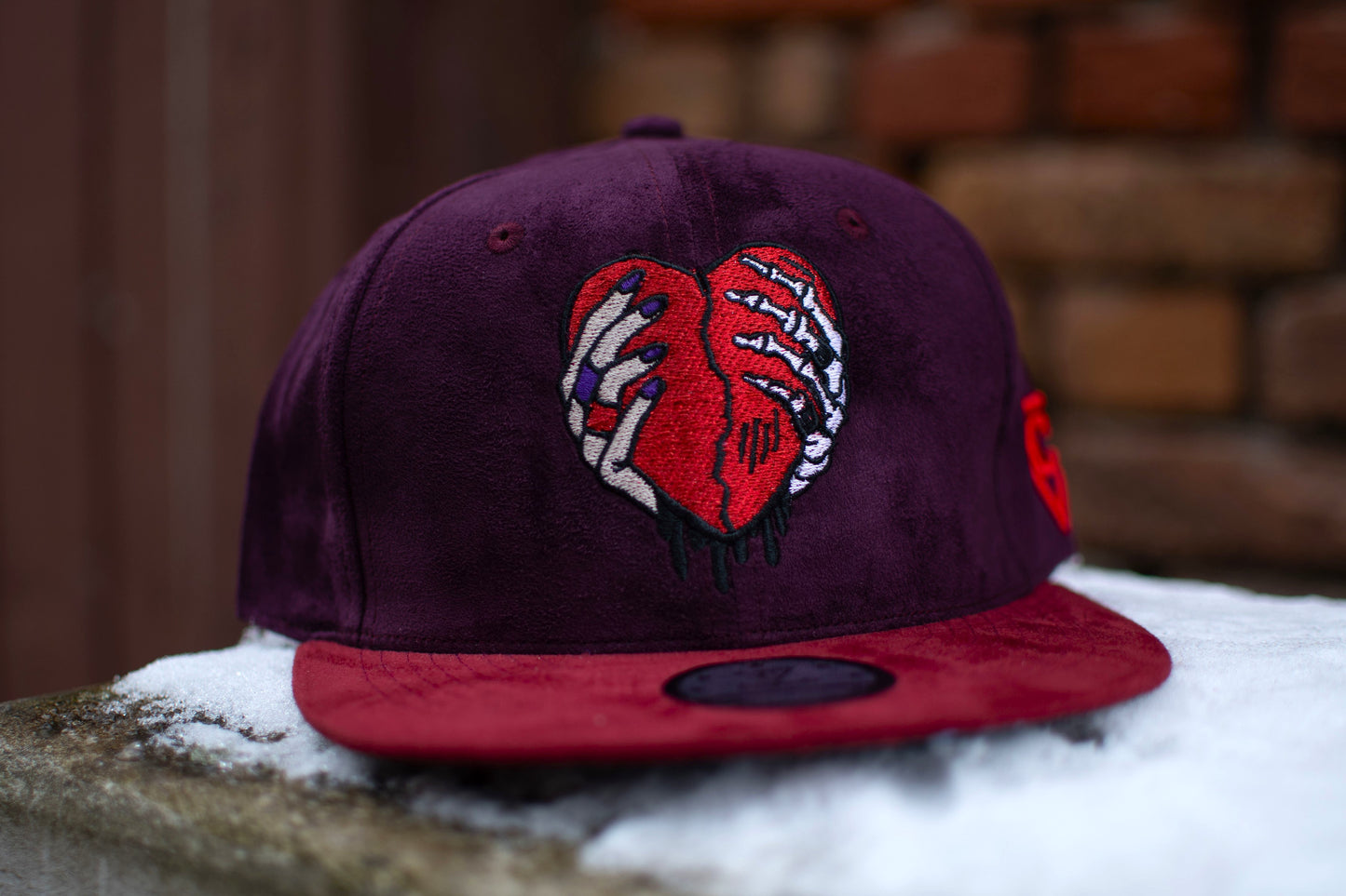 Close up of a purple and red suede snapback hat from the high-end headwear brand Capiche