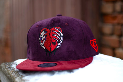 Close up of the Savior snapback cap from Capiche Caps in a beautiful dark purple and red suede fabric