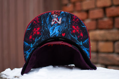 Close up from the Savior snapback from Capiche Caps. The design shows an angel holding a heart